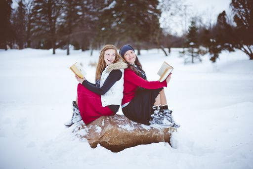 A shallow focus shot of two female sitting on the rock back to back while talking