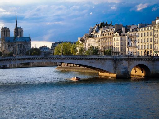 A beautiful shot of a river over the river Seine in Paris and the Notre Dame cathedral in the behind