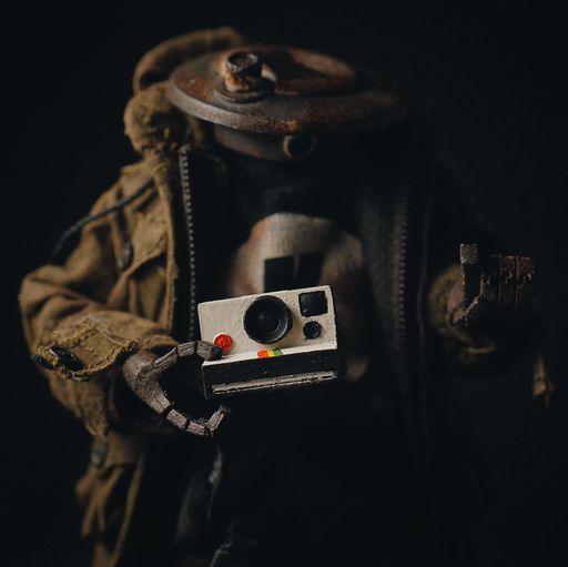 A closeup shot of a headless soldier miniature holding an old camera