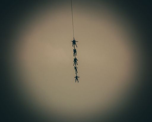 A silhouette of people hanging on a rope in the air