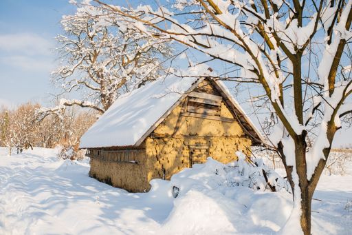A hut in a field covered in the snow under the sunlight in winter