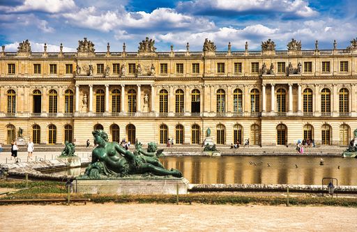 A low-angle closeup of Palace of Versailles royal residence building cloudy sunlit sky background