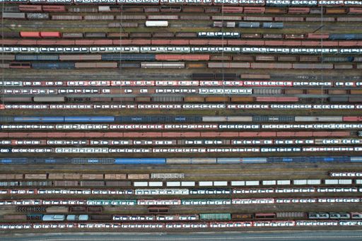 An aerial view of a train yard with multiple railway lines, with cars on top
