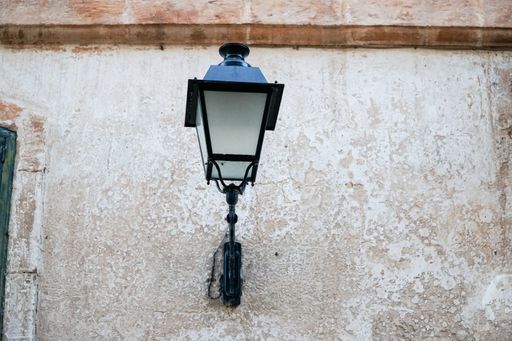 A low angle shot of a vintage metal lamp hanging on an old building wall in Paris, France
