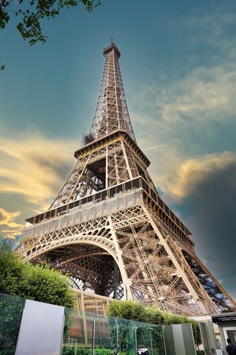 A low angle shot of the Eiffel Tower under a rainy cloudy sky