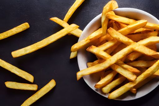 a top view of french fries on a white plate on a black background