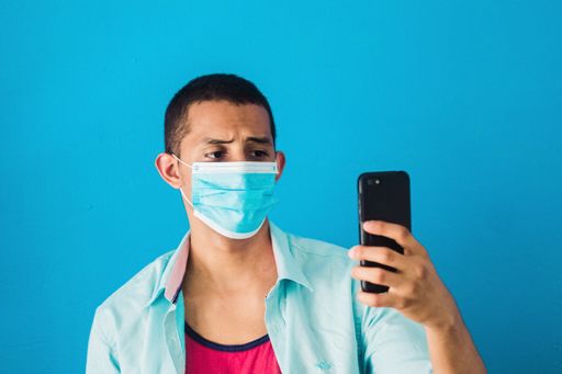 A young male taking a selfie in a protective face mask