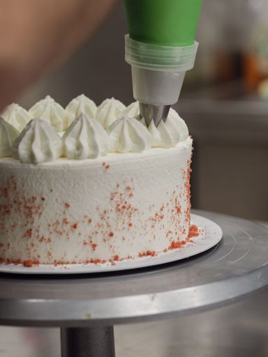 hand pof chef making for icing a red drip cake in the professional kitchen lab