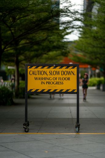 A caution, slow down sign board of washing the floor in progress in Marina Bay, Singapore. Vertical Shot.