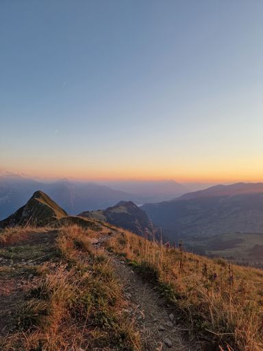 A beautiful view from a mountain peak with vast hills around it under the golden glow of the sunrise