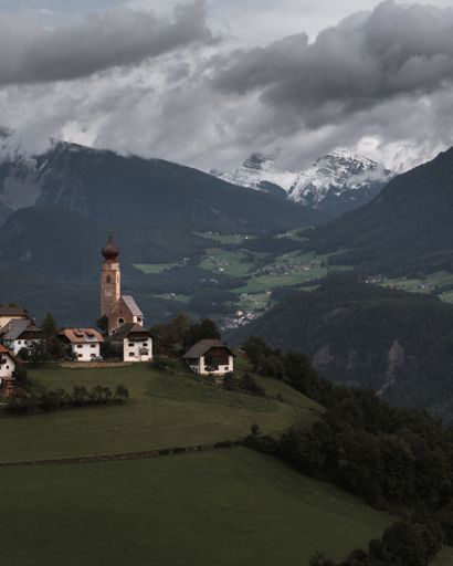 A vertical shot of a small village in Mittelberg with the St Nicholas Church steeple