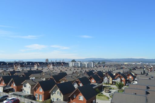 An aerial view of a row of residential houses with gray tiled roofs in daylight in blue sky background
