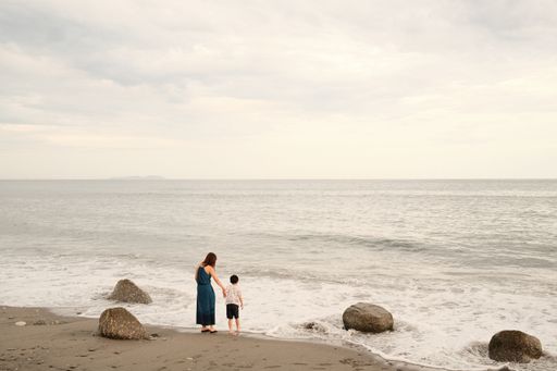 The little boy with his mother standing on the shore and looking at the sea.