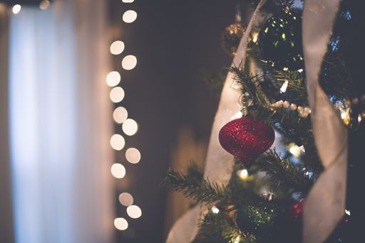 A closeup shot of a beautiful red ornament on the Christmas tree with bokeh lights in the background