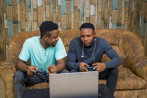 Young African men playing a video game on a laptop at home