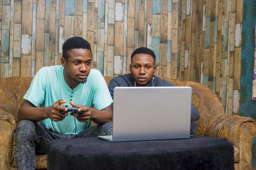 Young African men playing a video game on a laptop at home