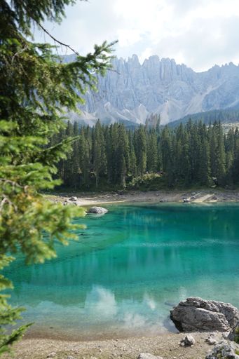 A vertical shot of Lake Carezza against the background of the Dolomites. South Tyrol, Italy.