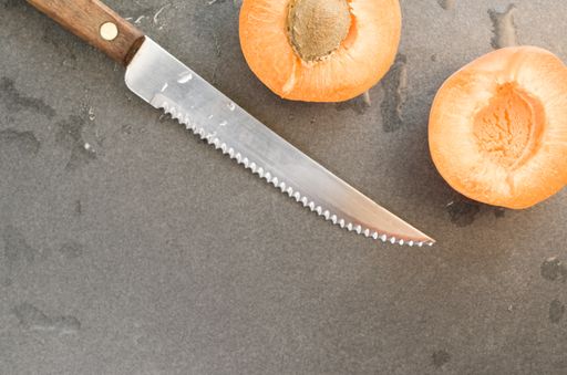 A top view shot of sliced plums and a knife on a smooth surface