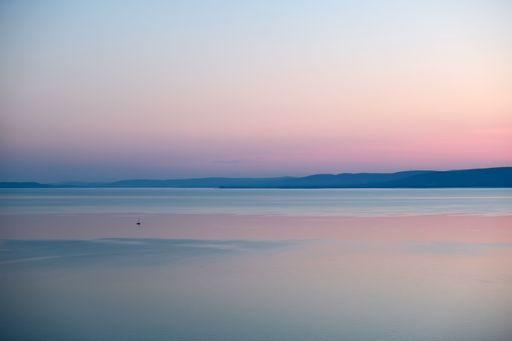 An aerial view of a beautiful sunset in the sea with a boat and a pink sky in the background