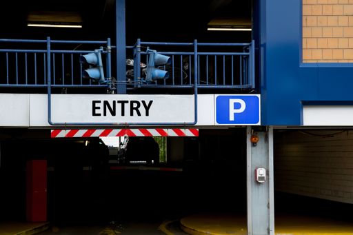 Entrance of a car parking garage with signal lights and the sign "Entry"