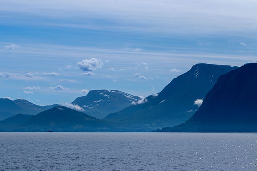 A breathtaking blueish view of West Norwegian fjord with mountains under blue cloudy sky