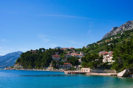 A scenic view of vacation homes on a hill near a sea