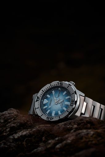A vertical of the Seiko watch on the rock against a black background.