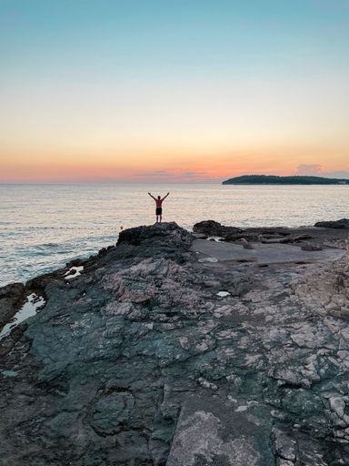 Beautiful sunset in croatia with an epic landscape. A man stretching his hands to the sky.
