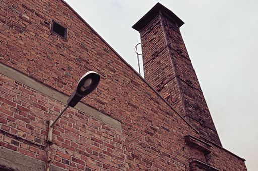 A low angle shot of a brick building with a chimney and a light on the side