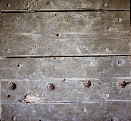 A high angle shot of an old damaged wooden floor with holes big rusty tacks