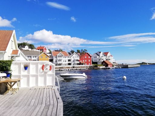 A beautiful shot of the houses near the sea from the village of Gjeving, Norway with a speedboat anchored on the harbor