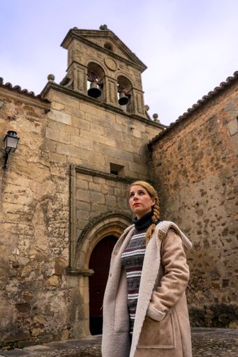 A vertical shot of a blonde young female traveling in a medieval location