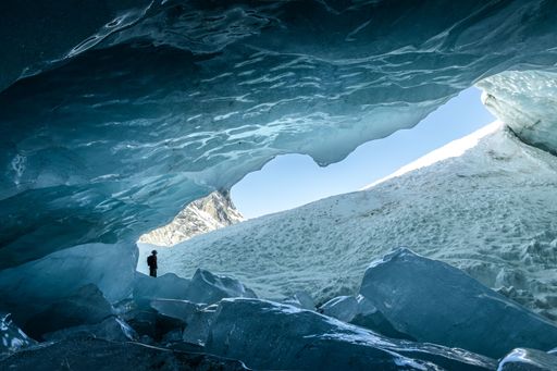 Silhouette of someone standing at the entrance of an ice cave in Zinal glacier, Valais Switzerland