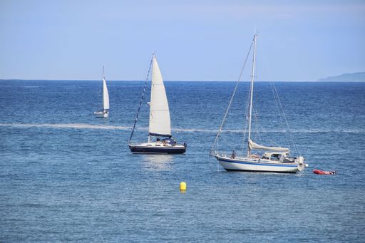 A closeup shot of white boats sailing along the Galician coasts of the Cantabrian Sea