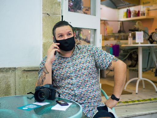A male with a medical mask sitting and talking on his phone at a cafe