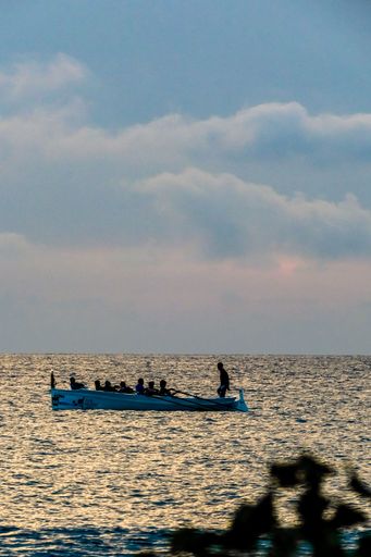 A vertical shot of the boat with rowers under the blue sky
