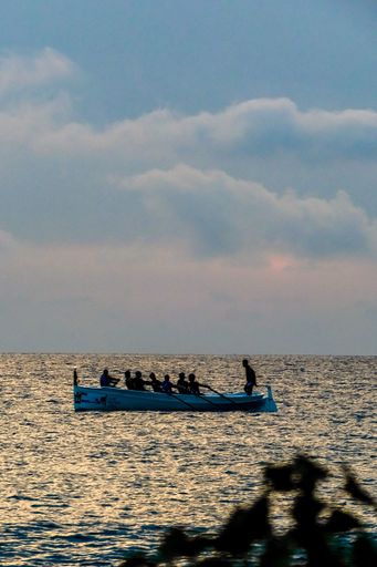 A vertical shot of the boat with rowers under the blue sky