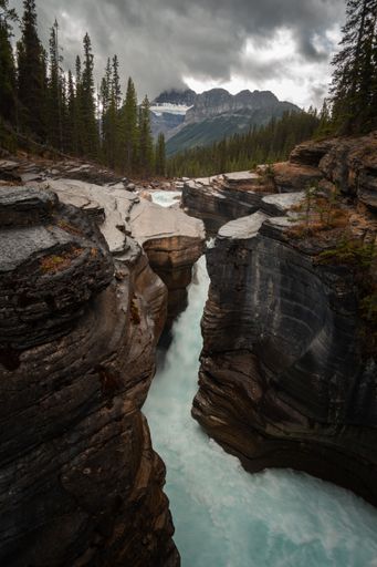 A flowing river surrounded by cliffs and dense trees