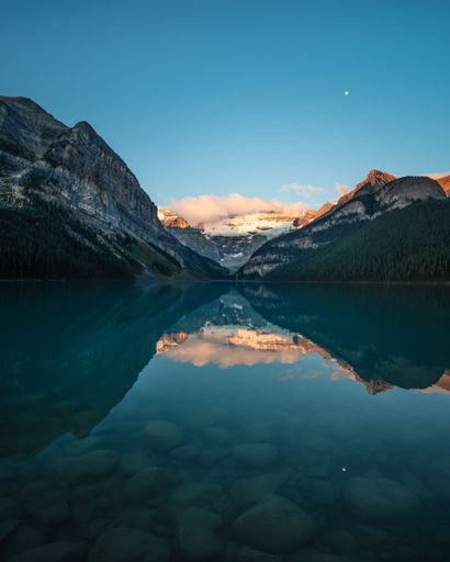 An aerial view of lake Louise surrounded by mountains and dense trees