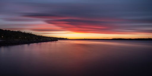 An aerial view of lake surrounded by trees during sunset