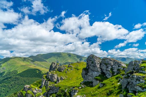 A landscape view of the rocky formations with green hills in the background against a blue sky