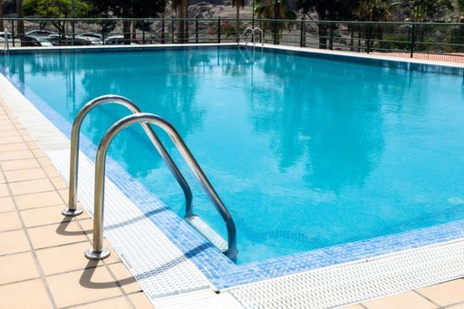 The swimming pool stainless steel handrail descending into tortoise clear pool water