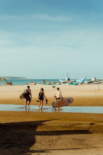 A vertical shot of surfers on the beach ready to swim
