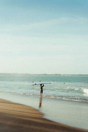 A vertical shot of a surfer on the beach with a beautiful sea in the background