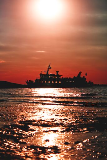 A vertical shot of a silhouette of a ship during the sunset