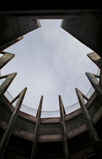 A vertical shot of the open roof of a building against the cloudy sky