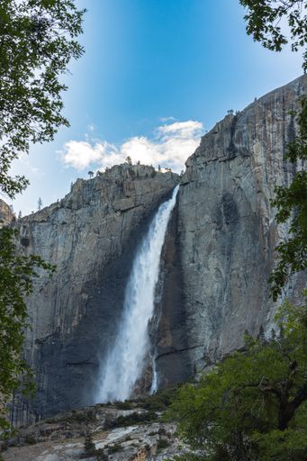 A vertical shot of the Yosemite Falls under blue sky in Yosemite National Park, California, USA