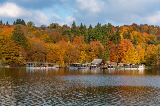 A beautiful landscape of the autumn forest at the shore of a lake with boats