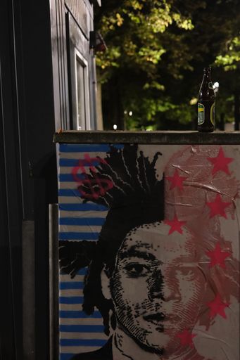 A vertical shot of an electricity box with punk graffiti and a beer bottle in Muenster, Germany