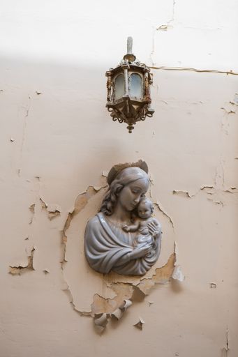 A vertical shot of a statue of the Virgin Mary with baby Jesus attached to a wall